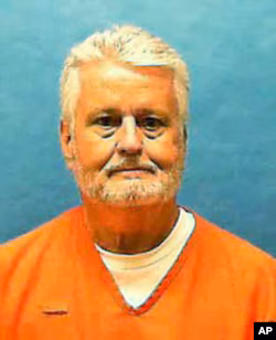 Bobby Joe Long with gray hair, a gray beard, and an orange prison shirt in his last prison photo